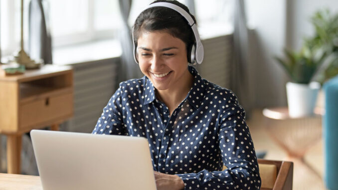Happy indian young girl wear headphones watching listening online course